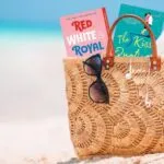 a beach bag with romance book covers poking out