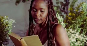 black woman reading against backdrop of white flower sprays