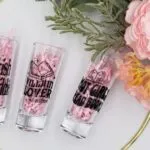 three shot glasses with text like "Hot Girls Read Books" with flowers in the background