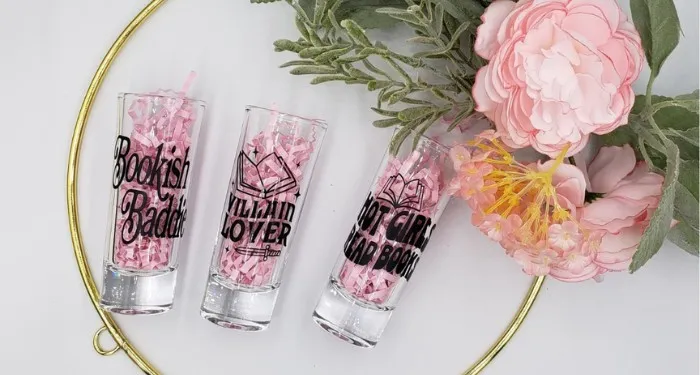 three shot glasses with text like "Hot Girls Read Books" with flowers in the background