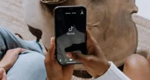 brown skinned hands holding a phone with tikok on it