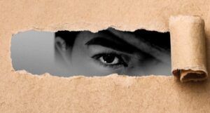 butcher style paper torn and rolled back to reveal fragment of black and white face with one eye staring out