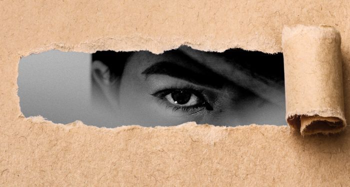 butcher style paper torn and rolled back to reveal fragment of black and white face with one eye staring out