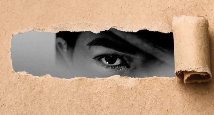 butcher style paper torn and rolled back to reveal fragment of black and white face with one eye staring out