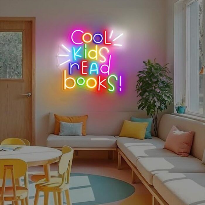 Image of a play room with a large, lit neon sign. The words read "cool kids read books" and the letters are multicolored with white accents.