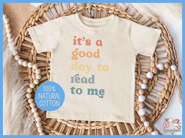 an ivory colored tshirt with rainbow words that say "it's a good day to read to me."