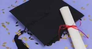 Image of a mortar board and diploma on a purple background