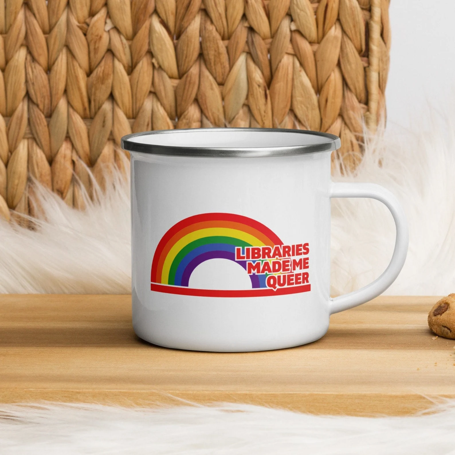 image of a white camping style mug. It has a rainbow on it, with the words "libraries made me queer" in red. 