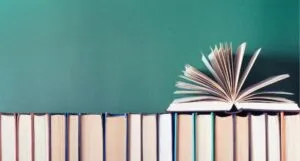 open book fanned on top of row of books with spines faced away