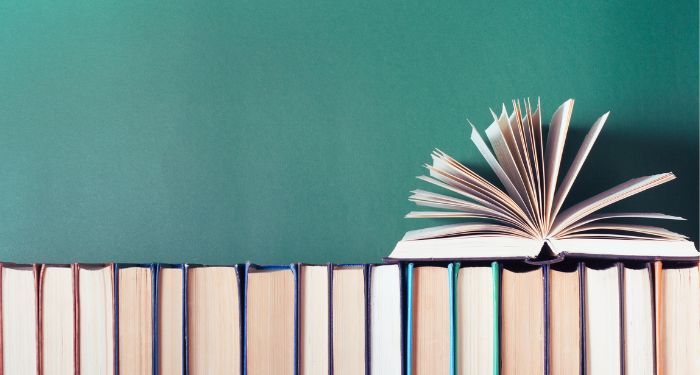 open book fanned on top of row of books with spines faced away.jpg.optimal