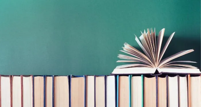 open book fanned on top of row of books with spines faced away