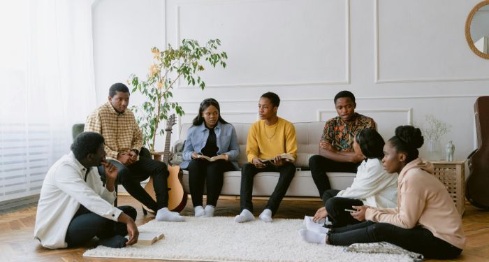 Black people of various skin tones sitting in a circle and discussing books