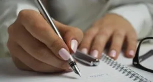 light tan skin hands with a manicure writing with a fountain pen in a notebook