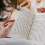 someone reading a book with fruit in the background