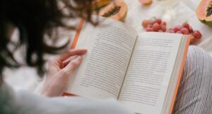 someone reading a book with fruit in the background
