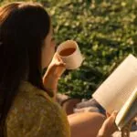 a woman reading outside while drinking tea