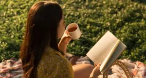 a woman reading outside while drinking tea