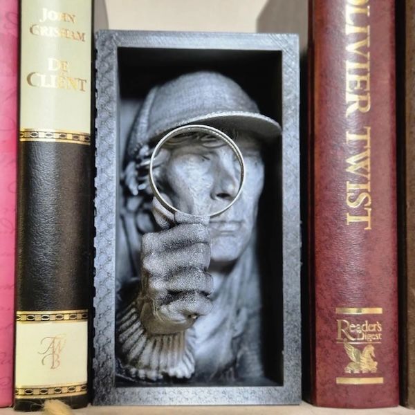a grey book nook insert of a bust of Sherlock Holmes holding a magnifying glass up to his face