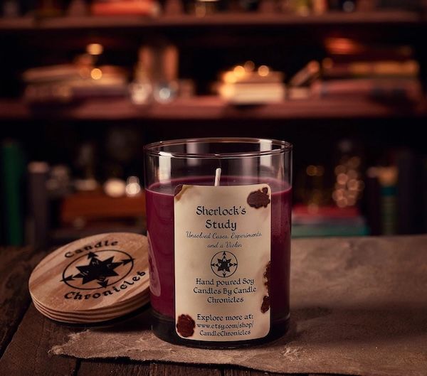 a magenta wax candle in a glass jar with a label that says Sherlock's Study: Unsolved Cases, Experiments, and a Violin