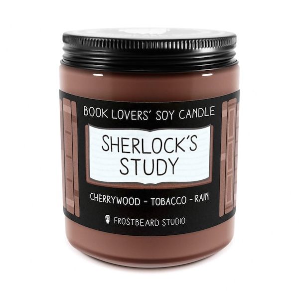a brown wax candle in a clear glass jar with a black lid. The label on the candle says Book Lovers' Soy Cnadle: Sherlock's Study - sherrywood, tobacco, rain