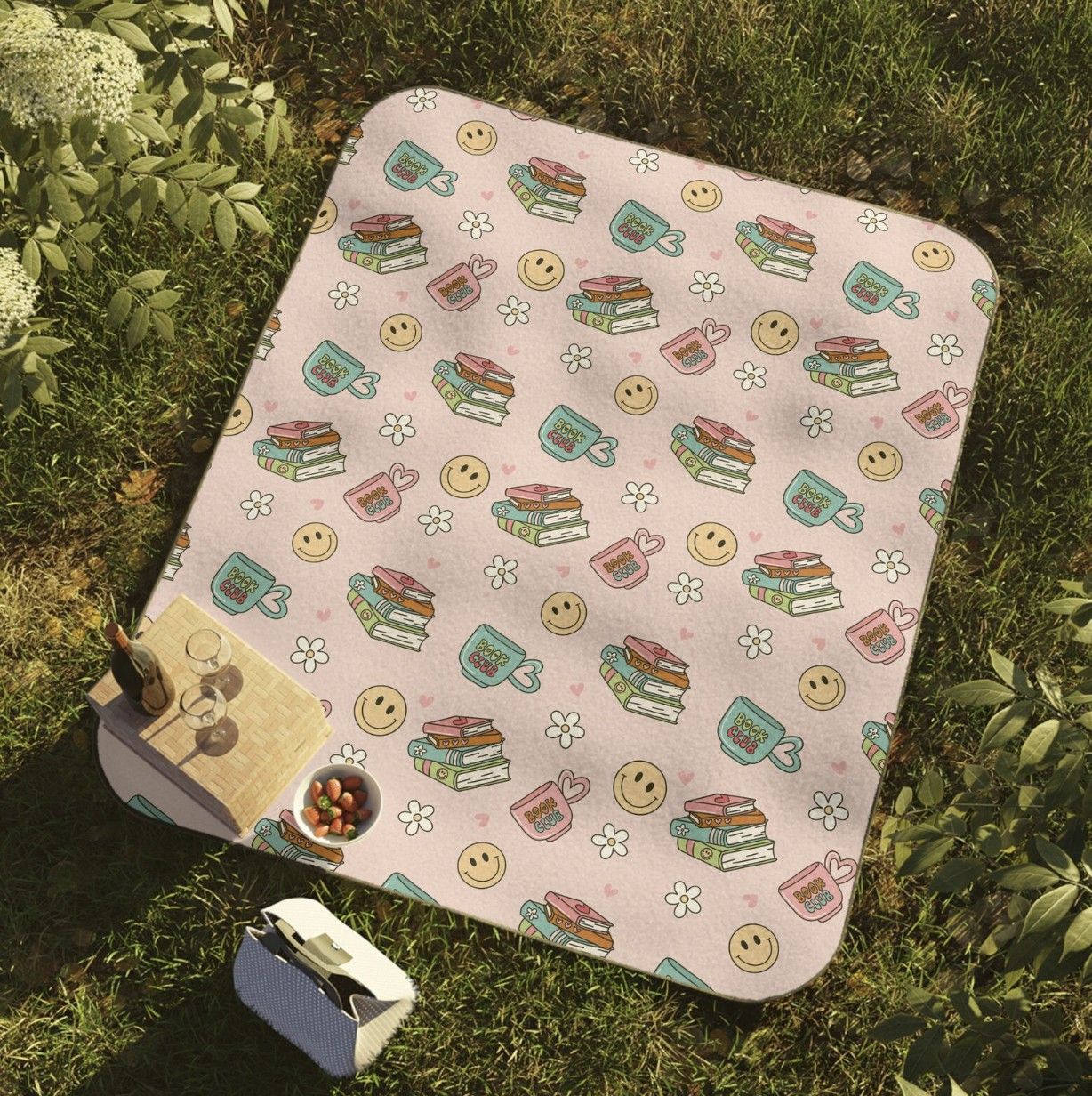 Imagen de una manta de picnic rosa con montones de libros ilustrados y corazones
