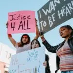 Image of three people holding protest signs