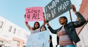 Image of three people holding protest signs