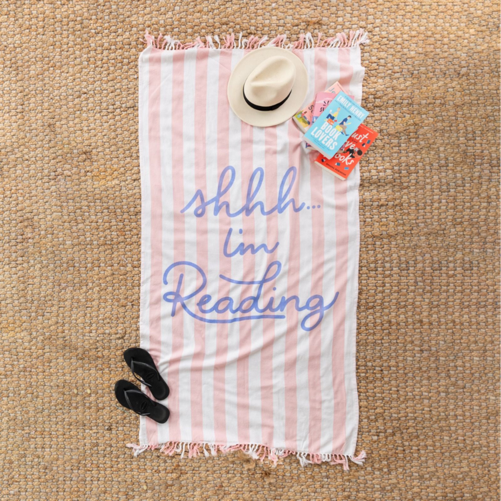 Pink and white striped beach towel with "shhh...I'm Reading" in blue cursive