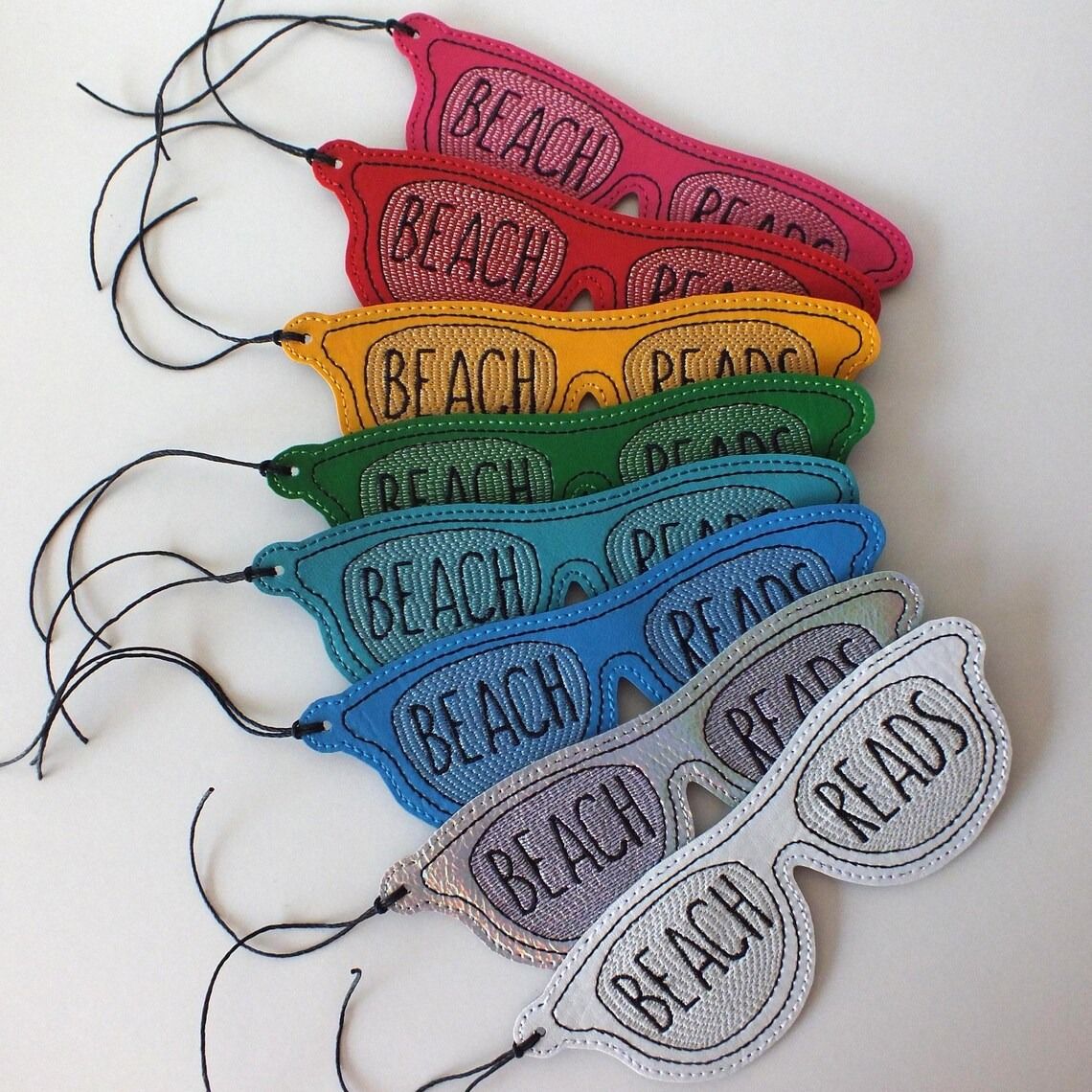 Fabric bookmarks in the shape of sunglasses with "Beach Read" embroidered on the lenses