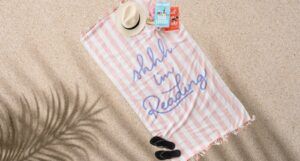 a striped beach towel with the text "Shhh... I'm reading"