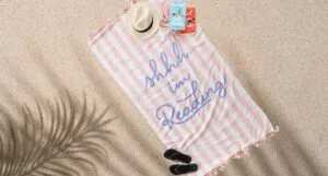 a striped beach towel with the text "Shhh... I'm reading"