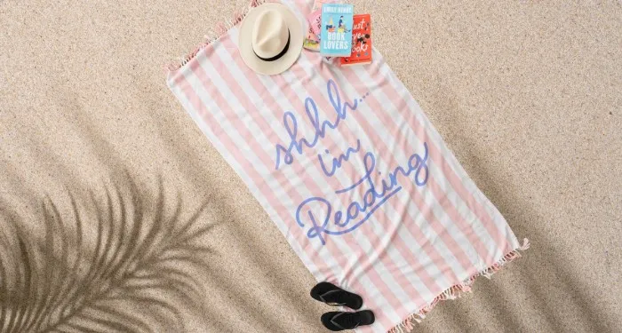 a striped beach towel with the text "Shhh... I'm reading"