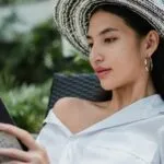 an Asian woman with light skin reading outside