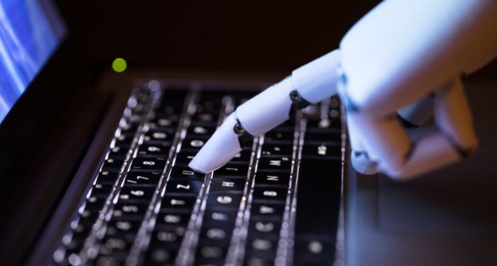 closeup of a robot's finger pressing a key on a laptop keyboard