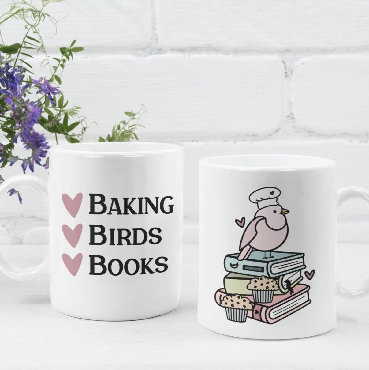 Image of a white mug with text "baking, birds, books" next to hearts and an illustration on the opposite side of a bird in a chef hat sitting on a pile of books
