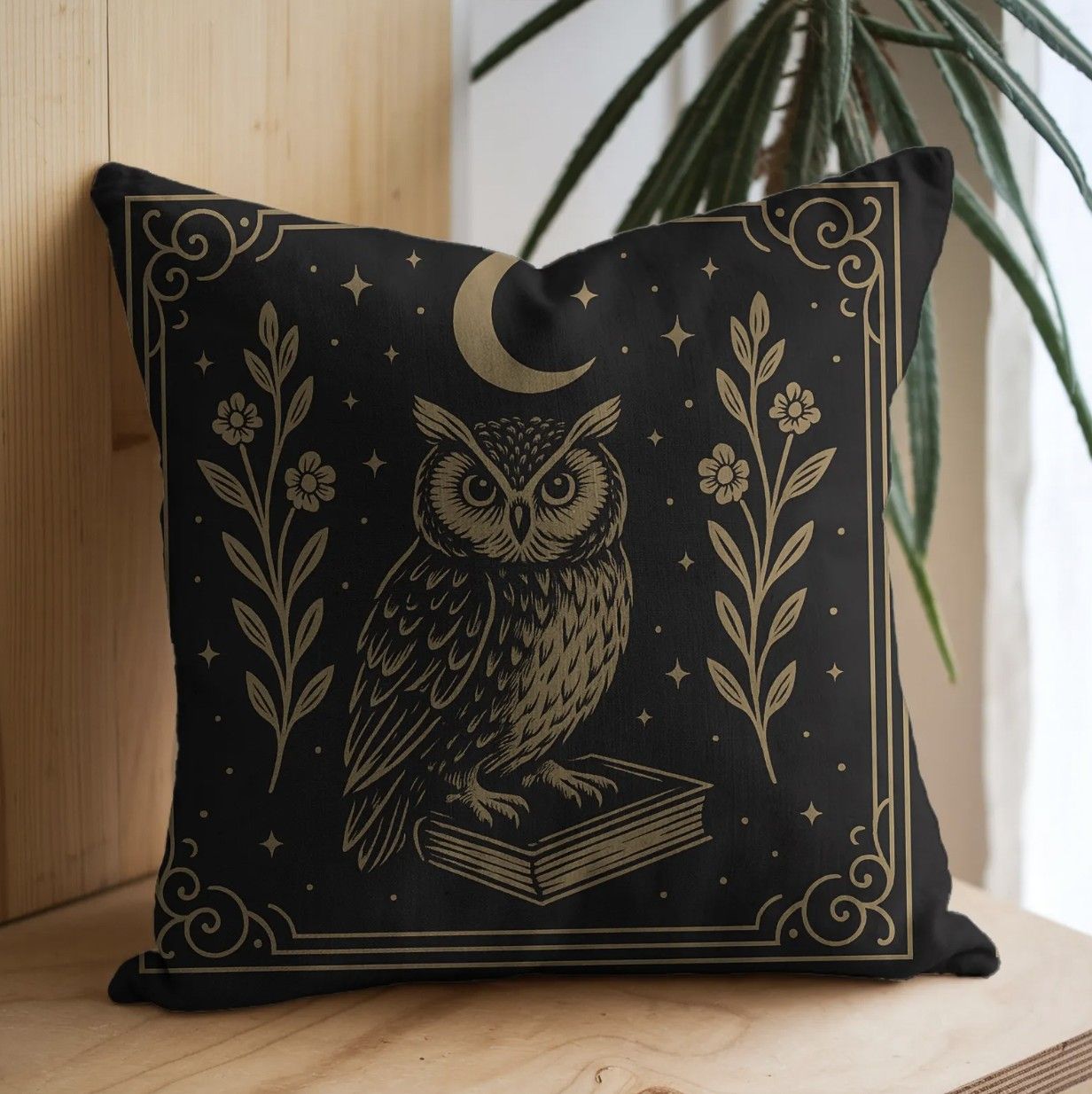 Image of a black and gold throw pillow with an illustration of an owl sitting on a book under a crescent moon