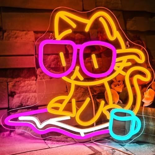 Image of an orange cat with pink glasses reading a pink book. There's a blue coffee mug next to the cat. 