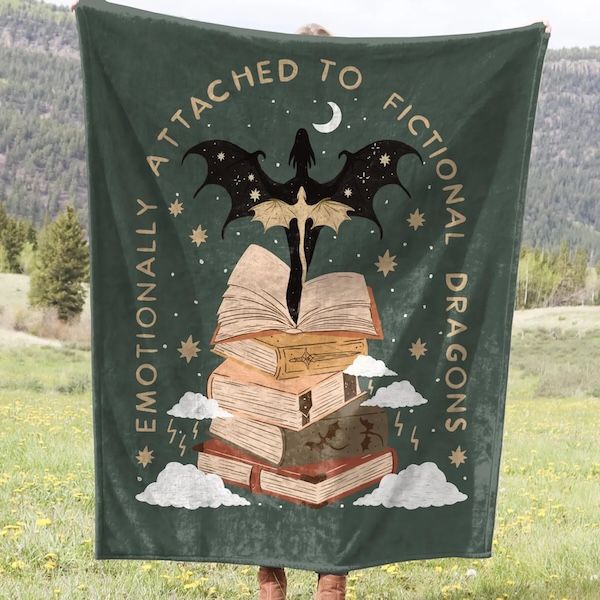 Se eleva sobre una manta verde y una sombra con un dragón y un montón de gráficos de libros. La limitación del gráfico es el texto que lee "emocionalmente conectado a dragones ficticios"