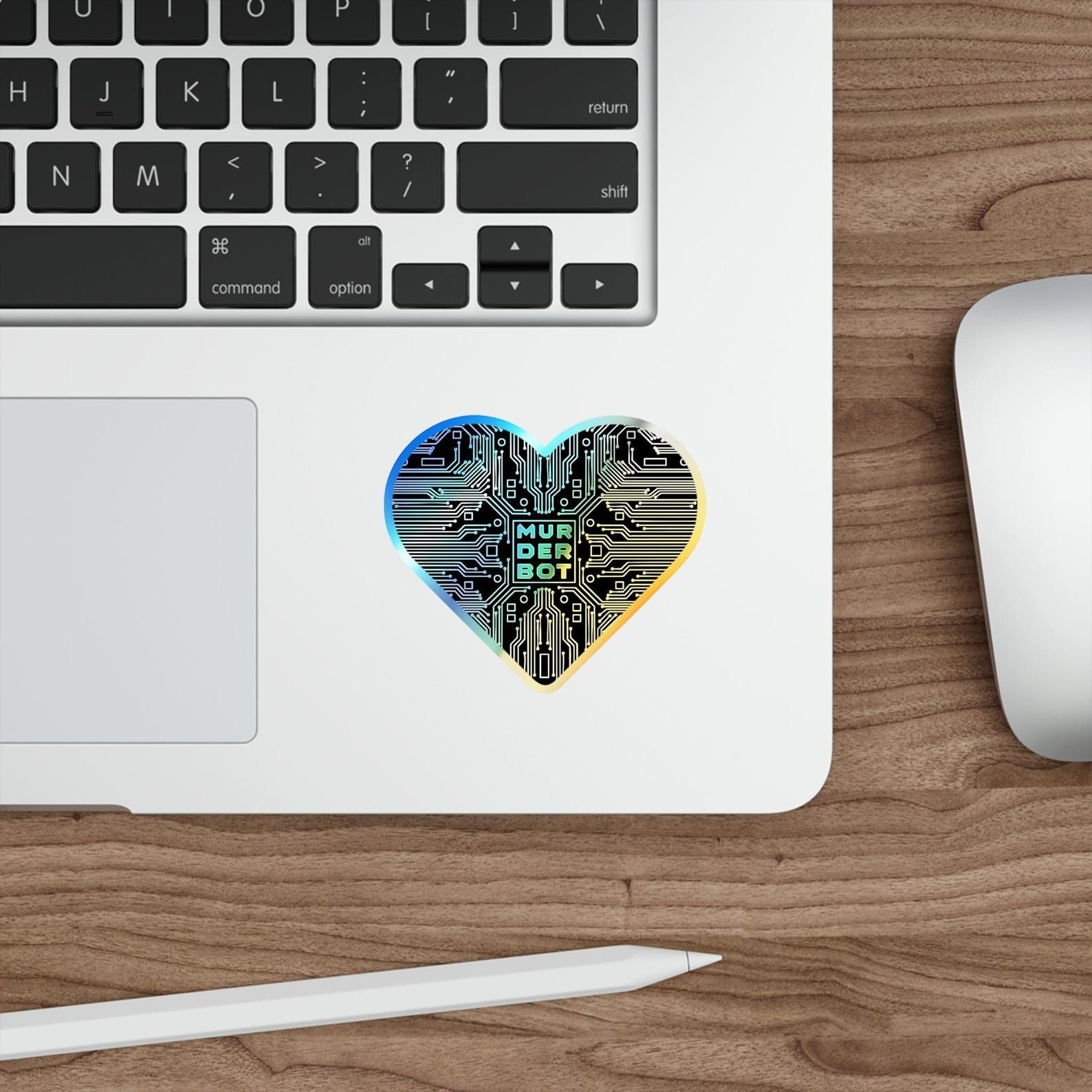 a heart-shaped holographic sticker with circuitry and the text "Murderbot"