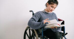 Image of a white person in a wheelchair reading a book