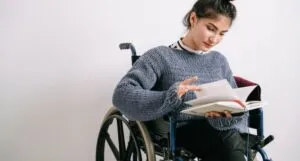 Image of a white person in a wheelchair reading a book