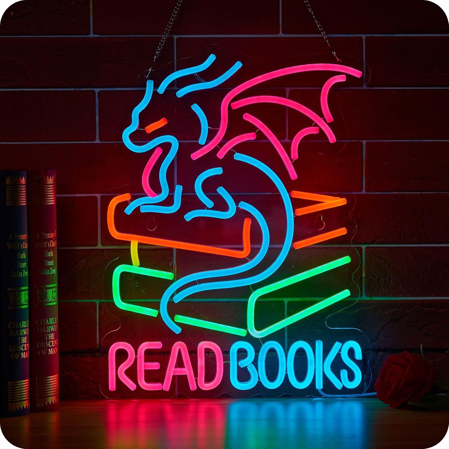 Multicolored neon sign featuring a little dragon on top of a stack of books. It says "read books."