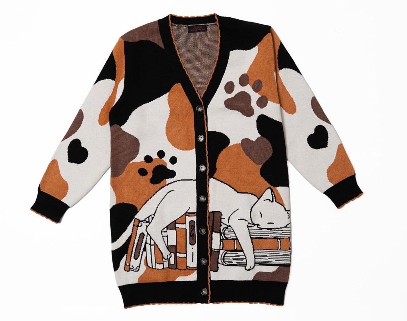 a calico print cardigan with an image of a cat lying on books