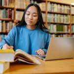 a woman with light brown skin studying in a library