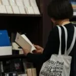 a fair-skinned older person reading a book in a bookstore