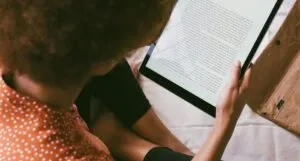a tan-skinned person with an afro reading off of a tablet