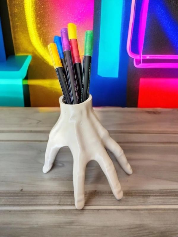 a pencil holder in the shape of a hand resembling "Thing" from Netflix's Wednesday. There wrist portion of the hand is a hole for placing pens/pencils in