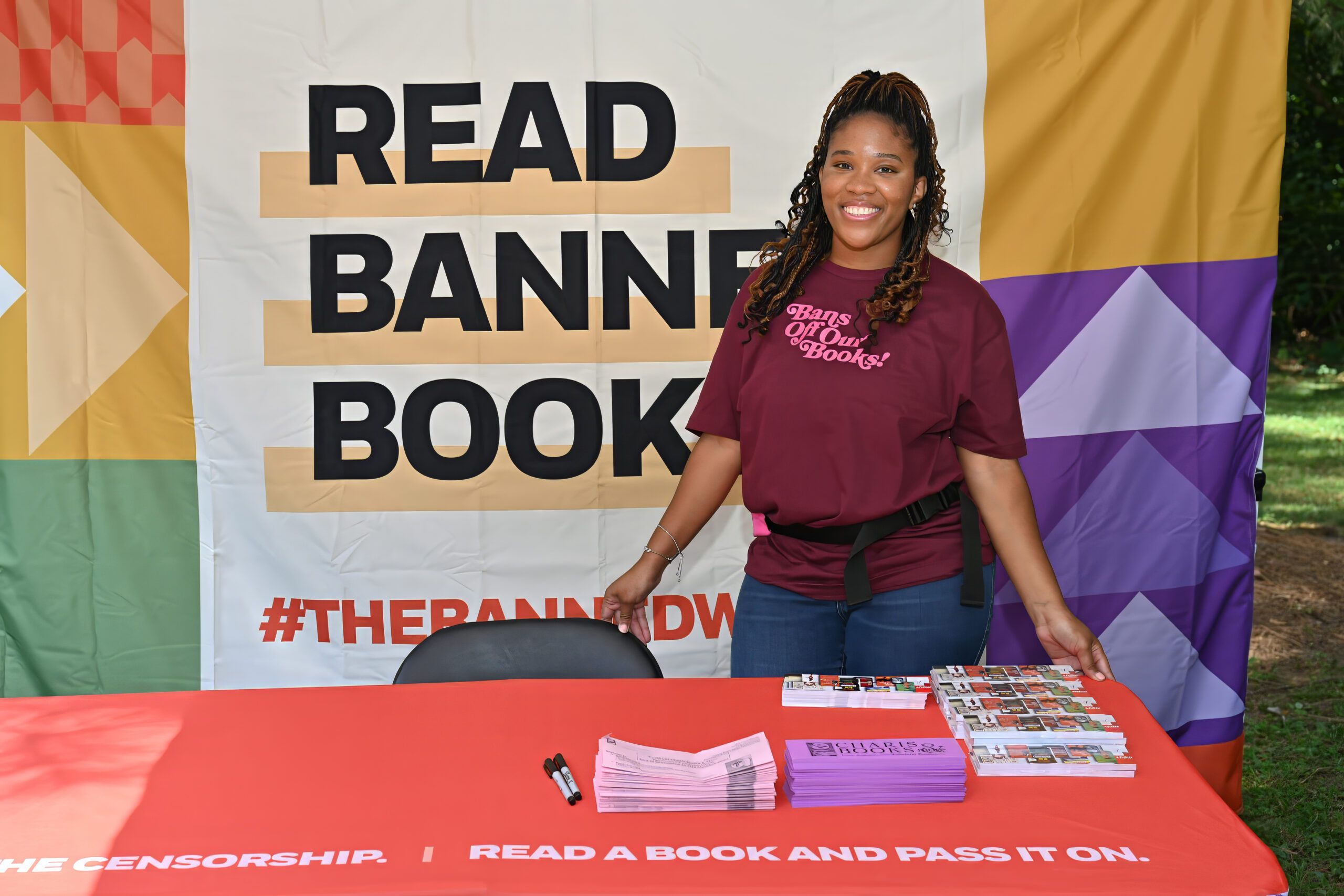 a Read Banned Books table with a smiling person with brown skin and long black hair