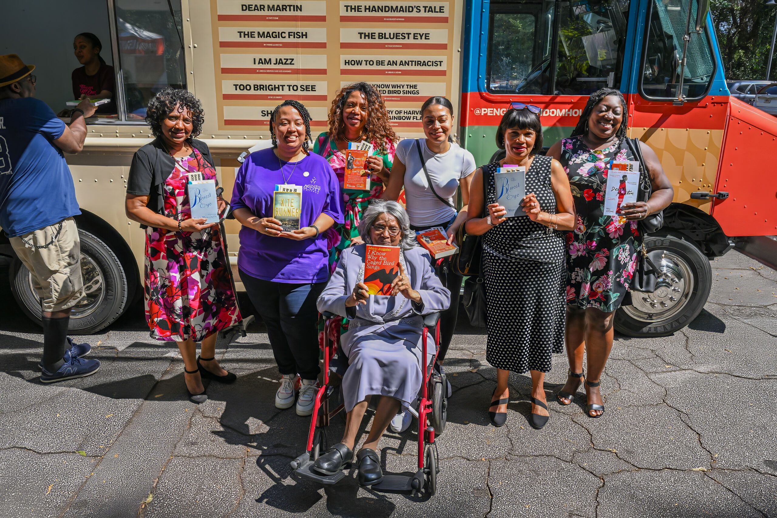 a group of adults posing with their books in front of the Banned Wagon