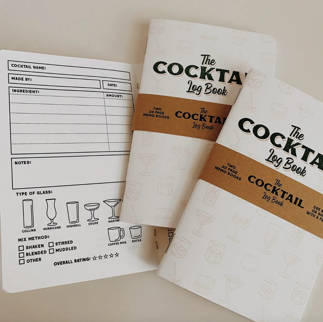 Image of a small paper journal titled "the cocktail log book" with an example page designed to record cocktail recipes